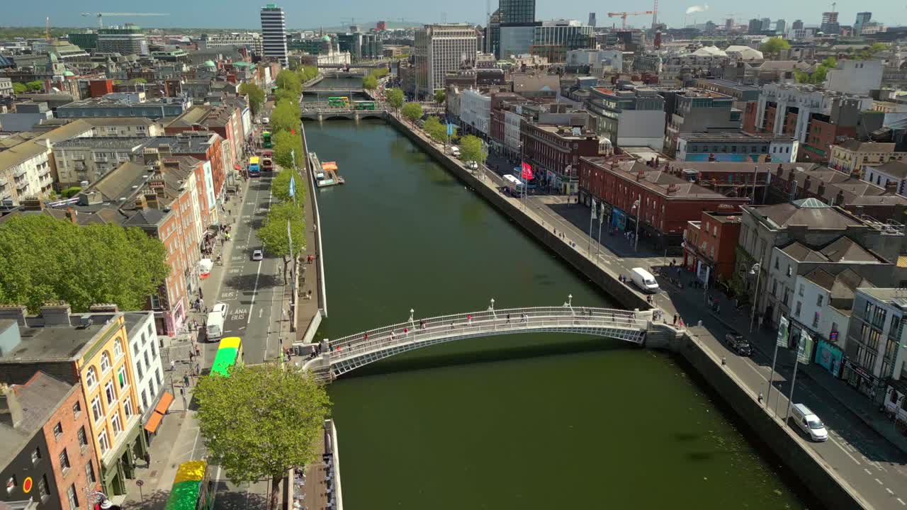 Wide rising aerial video of the River Liffey, the Ha'penny Bridge and Dublin City Centre in Dublin, Ireland on a bright and sunny day. Filmed in 4K, 60FPS and with Rec709 color.