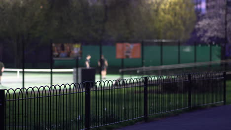 people playing tennis in the distance, night at king george's park, london uk