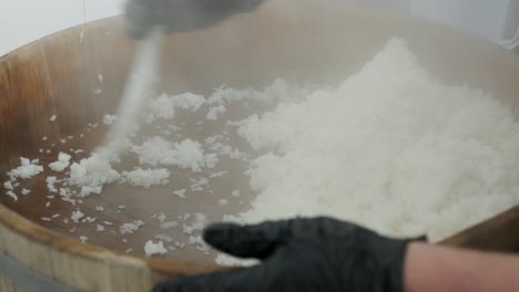 cook stirs hot rice in a wooden bowl