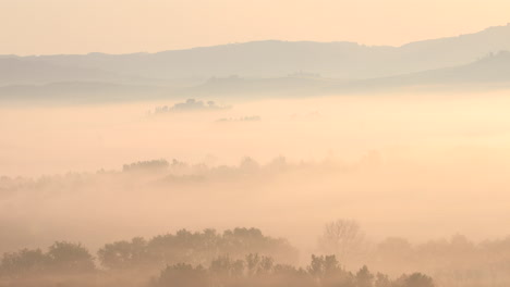A-misty-dawn-over-the-rolling-landscape-of-the-Val-d'Orcia-in-Tuscany,-Italy