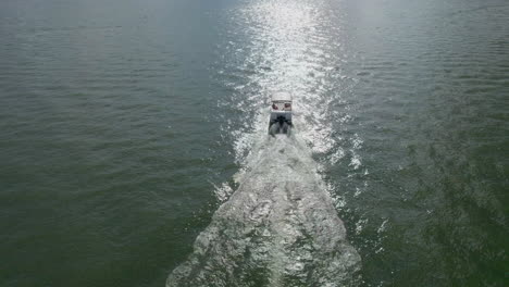 drone shot into the sun of boat on lake with boaters enjoying a beautiful day