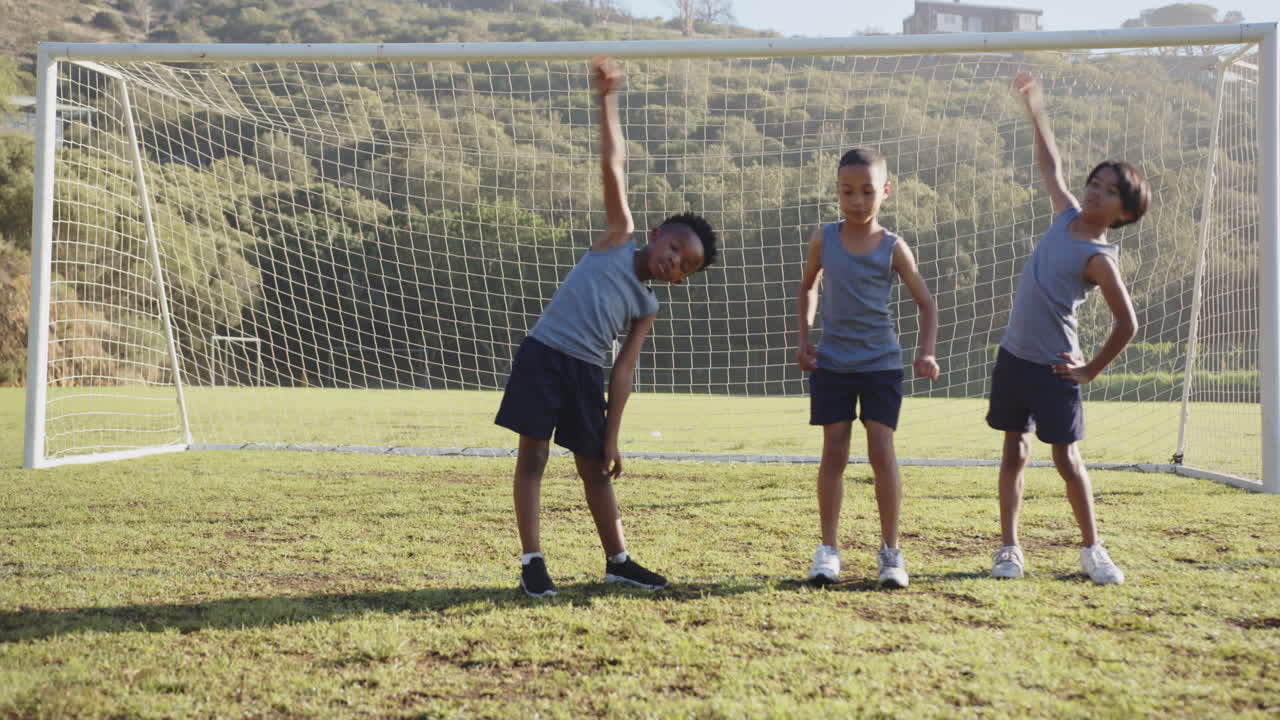 Stretching on soccer field, kids in school uniform warming up before game
