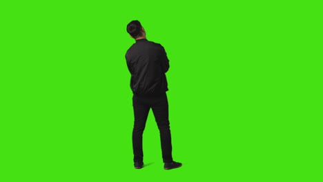 vista trasera de un joven aburrido o harto de pie y esperando contra el fondo de la pantalla verde 2