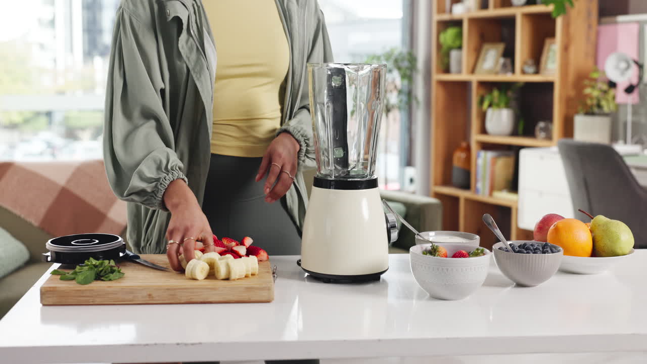 Woman preparing a smoothie with fresh fruit in the kitchen