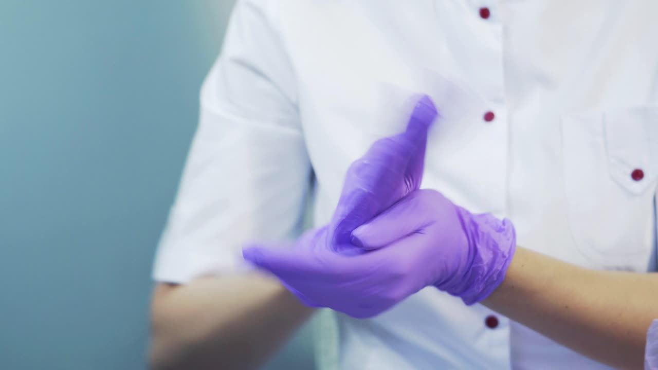 doctor cosmetologist in medical coat putting on gloves in a beauty salon. Healthcare and medical