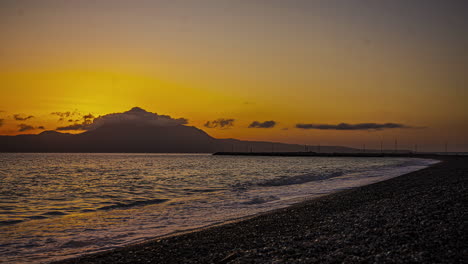 Time-lapse-sunset-mountain-background,-black-sand-beach,-waves-reaching-shore