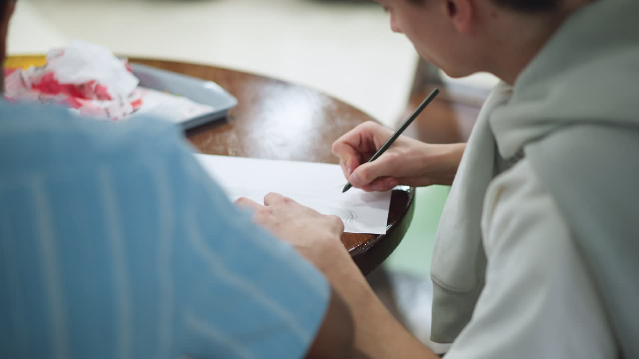 Back view of hand drawing tower shape on white paper, pen moving steadily over pencil lines under soft studio light, blurred background highlighting artistic process and intricate structural detail