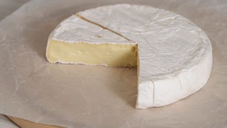 camembert cream cheese close-up rotating. head of goat milk cheese with white mold on wooden board. round head camembert cut into pieces delicious soft cheese camembert