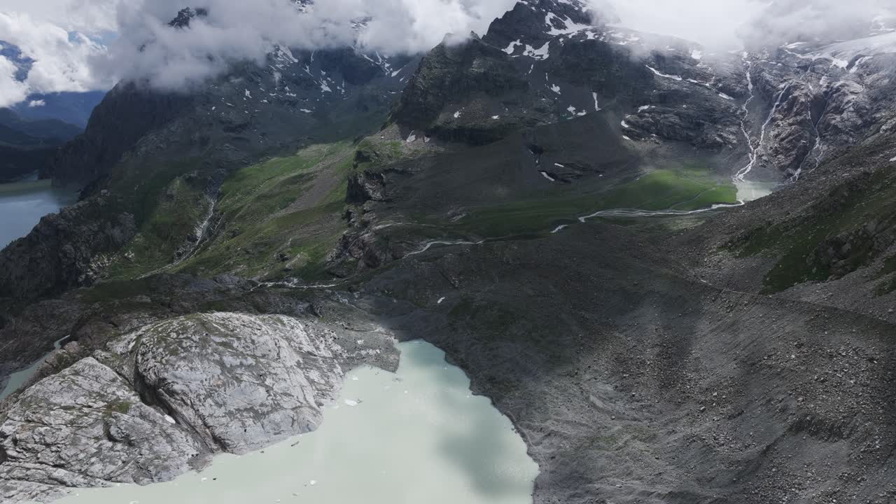 Fellaria gletsjerlagune med bjergkæde indhyllet i skyer i baggrunden om sommeren, Valmalenco i Italien.