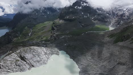 Fellaria-glacial-lagoon-with-mountain-range-shrouded-in-clouds-in-background-during-summer-season,-Valmalenco-in-Italy