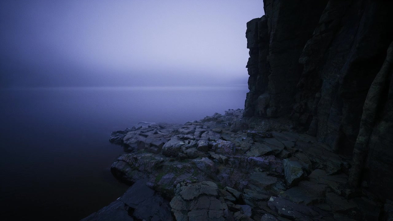 Majestic basalt cliffs extend into tranquil waters under soft foggy sky