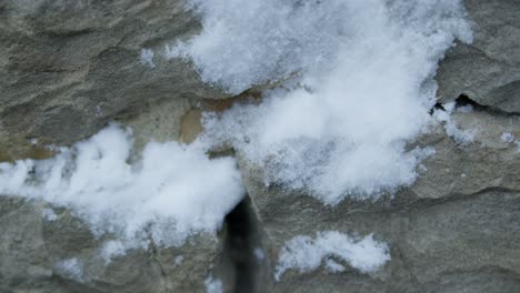 Zeitlupen-Nahaufnahme-Eines-Schneeballs,-Der-Auf-Eine-Graue-Steinmauer-Trifft-Und-Diese-Spritzt