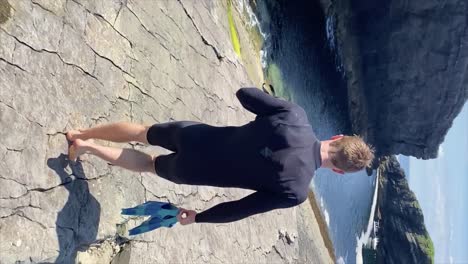 hombre en traje de neopreno que lleva equipo de snorkel camina hacia la costa