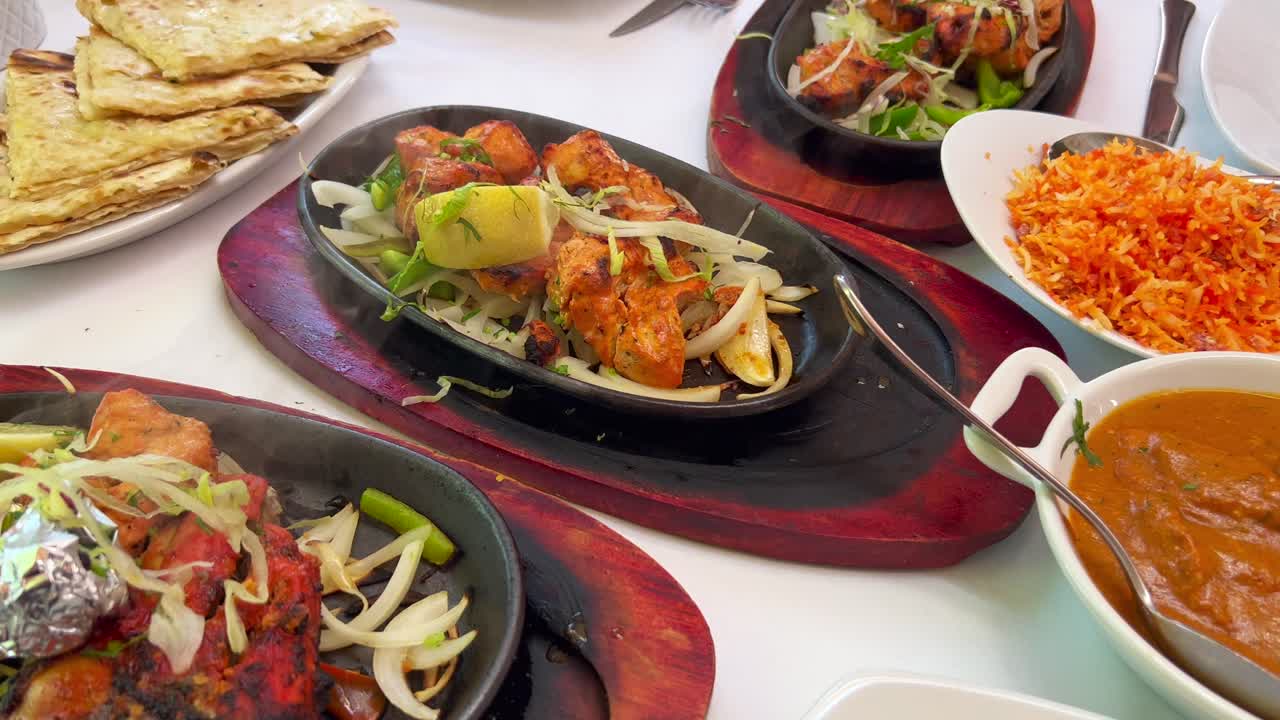 Traditional Indian Tandoori Chicken With Onions On A Hot Plate With Steam  Smoke, Butter Chicken, Cheese Naan Bread And Coconut Rice In A Restaurant,  People Enjoying Authentic Asian Cuisine, 4K Shot Free