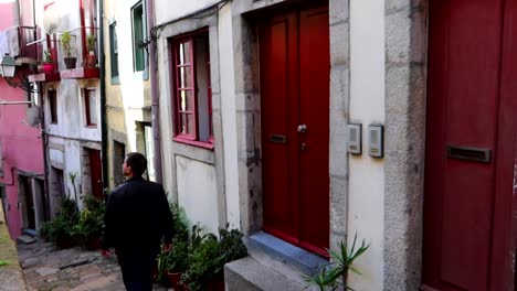 Red-doors-and-windows-with-a-man-walking-through-Rua-da-Pena-Ventosa-in-Porto,-Portugal