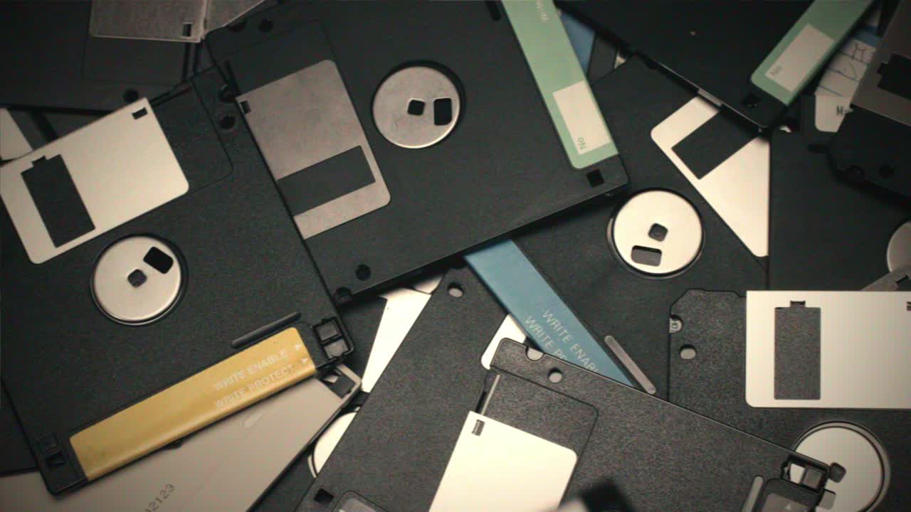 Hand holding a floppy disk surrounded by many more