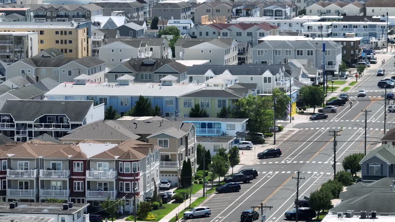 Aerial view of Wildwood, New Jersey, showing coastal residential architecture, colorful beach houses, streets and summer vacation atmosphere. Ocean, beach and amusement park in distance. Wide shot