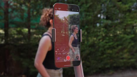 woman outdoor recording video with smartphone mounted on ai tracking gimbal stabilizer. closeup shot