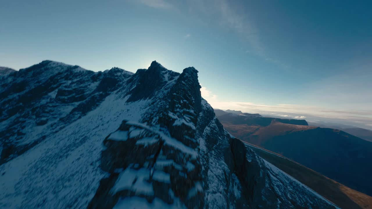 vuelo cinematográfico de drones a lo largo de la cumbre nevada de las montañas noruegas durante la iluminación del amanecer en el fondo - vuelo fpv