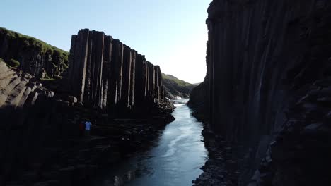 a bru river in studlagil canyon, iceland with basalt rock columns, front view, moving in