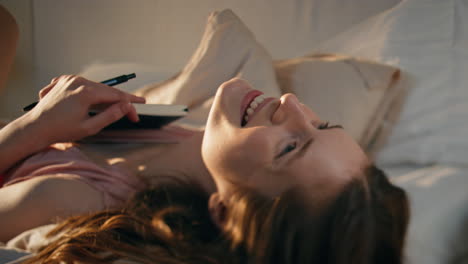 smiling girl lying bed in morning sunlight closeup. attractive female holding