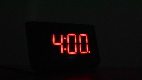 alarm clock going off at 4:00 am in dark room. hand reaches out and stops alarm