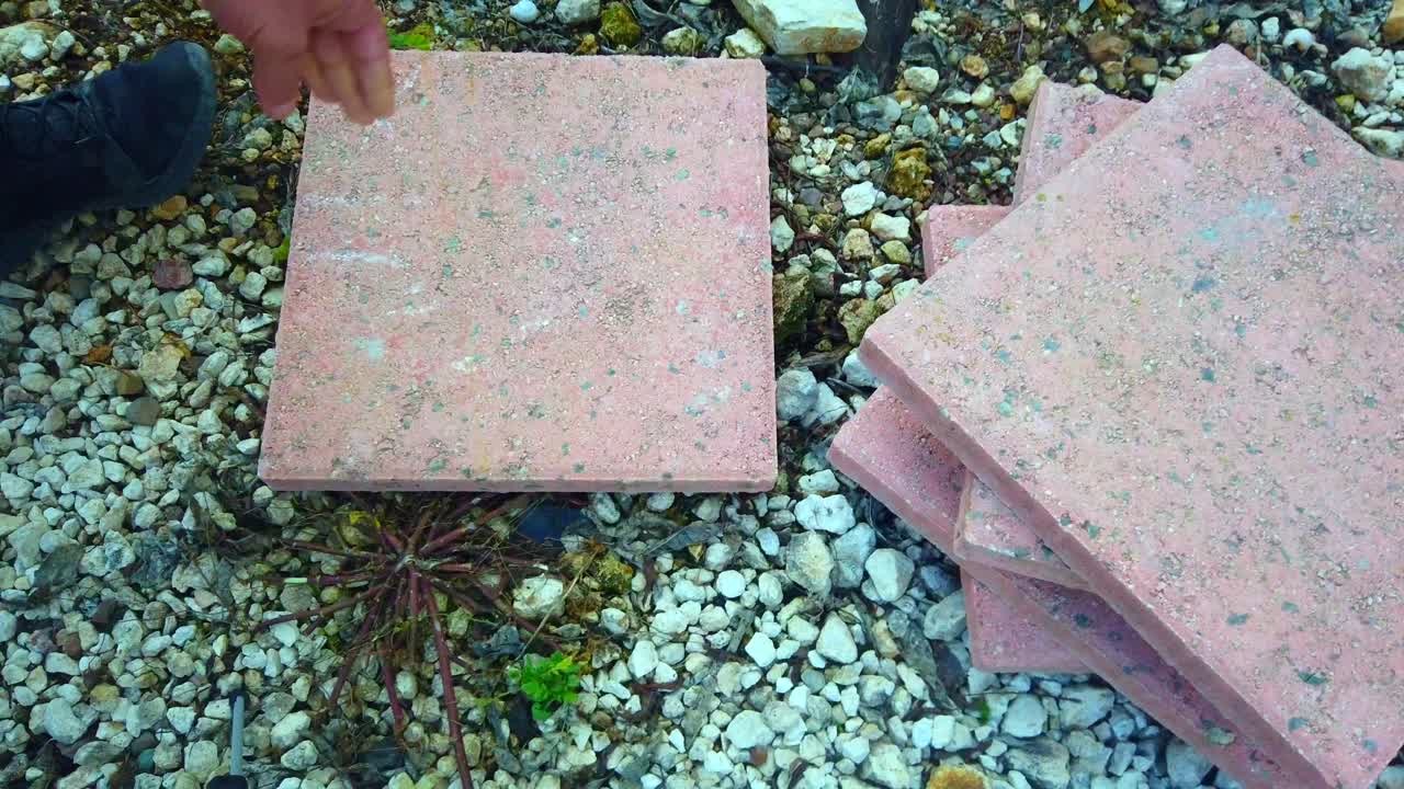 Filmato ravvicinato di una lastra da giardino posata a terra. La clip è ideale per il miglioramento della casa e la manutenzione del giardino.