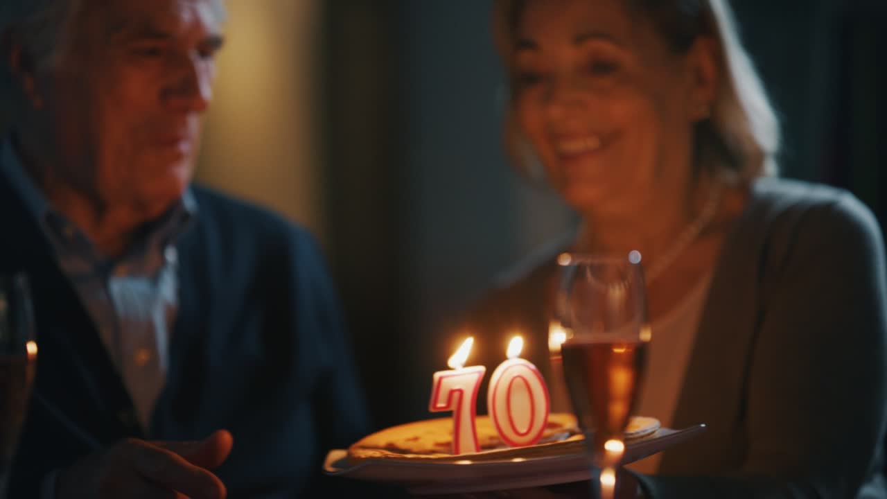 Un uomo anziano sta soffiando le candeline di una torta fatta con amore da sua moglie per una festa di compleanno a casa