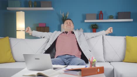 Home-office-worker-man-yawns-and-relaxes-at-the-camera.