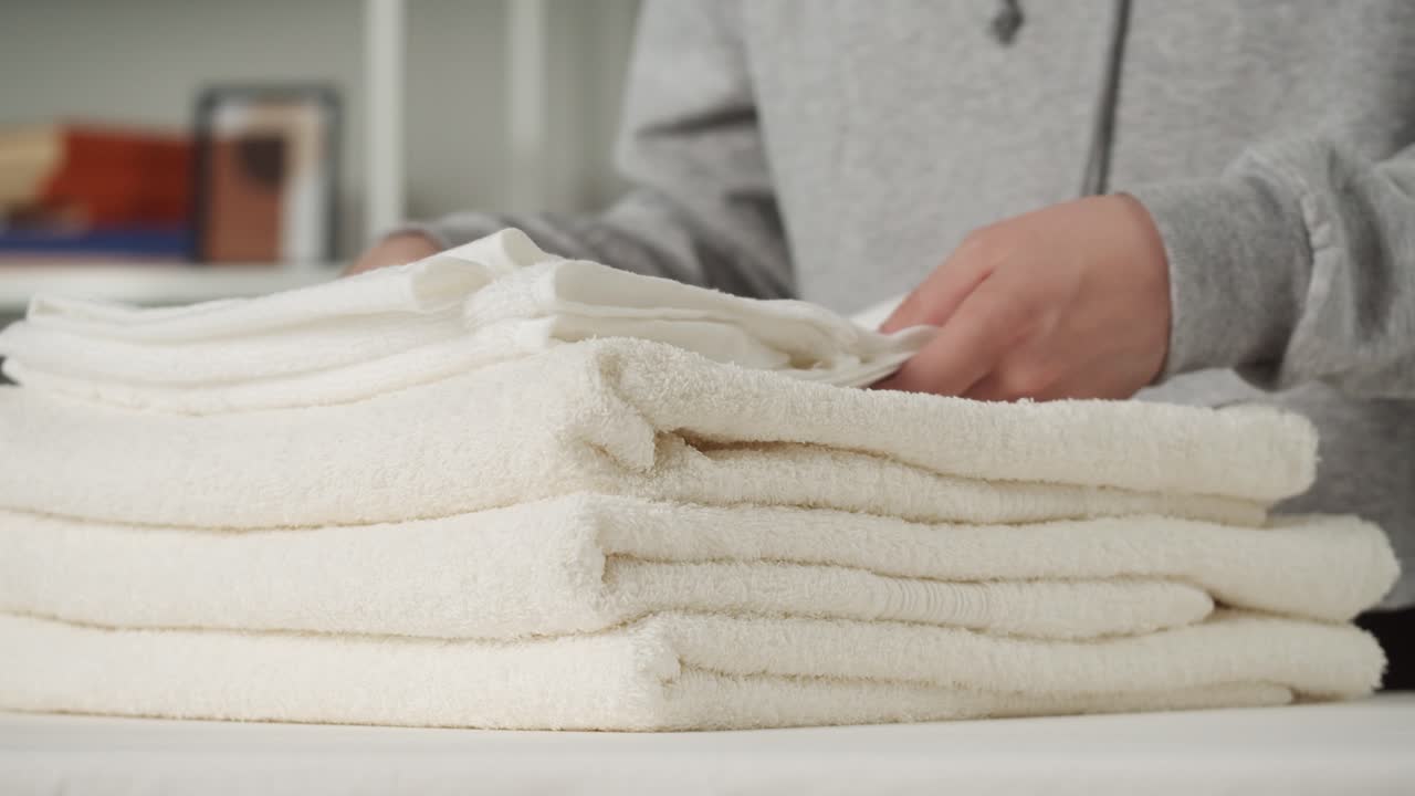 Close-up of Hands Folding and Stacking Clean White Towels