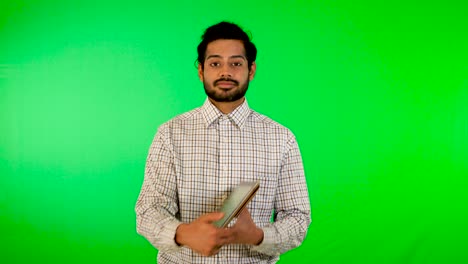 guy using mobile - tablet with green screen and green background indian guy with green screen