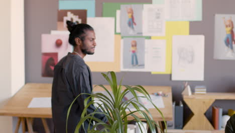 young man approaching to his colleague in animation studio and discussing together a new project on desktop computer