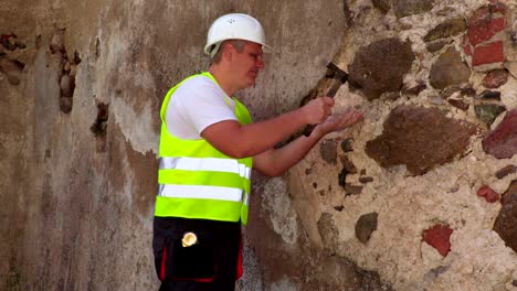 ingeniero con martillo comprobando el yeso de la pared vieja