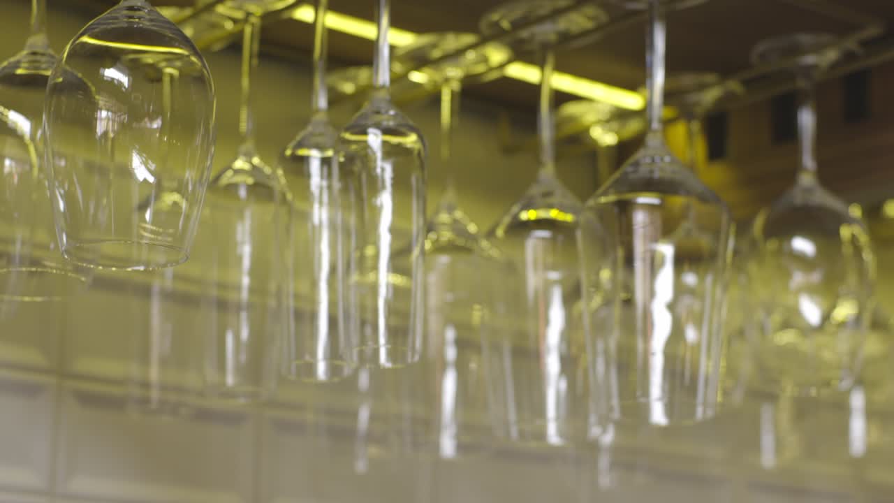 Bar alcohol glasses hanging from the ceiling create a unique and captivating atmosphere, showcasing a wide variety of glassware and adding a touch of sophistication to the bar's decor