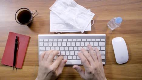 manos de una persona que trabaja en la computadora y limpia con gel de alcohol
