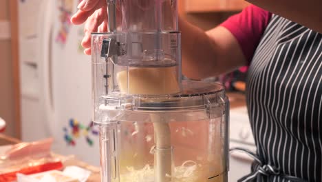 Using-a-food-processor-to-grate-Gruyere-cheese-made-from-whole-cow's-milk---side-view-in-slow-motion