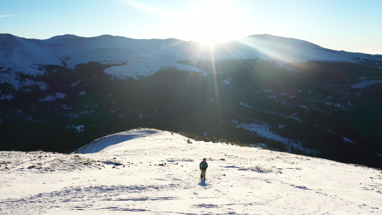 록 키 산맥 풍경에서 화창한 겨울 날 오르막 눈 위를 걷는 풀어요와 남성의 공중보기