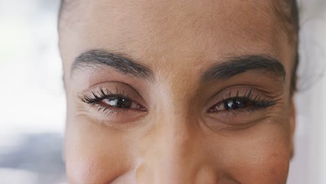 portrait close up of happy biracial female barista smiling in her coffee shop