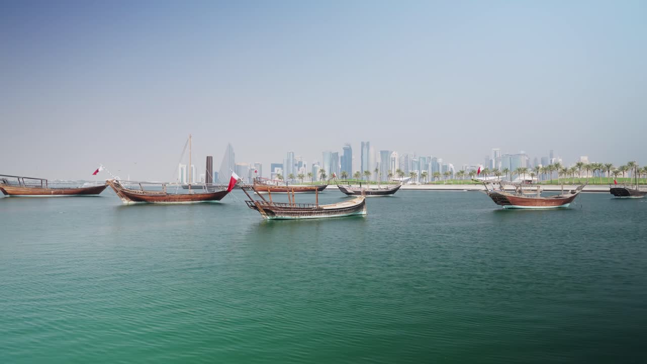 Boats with Qatar flags swinging in doha city marina and skycrapers skyline