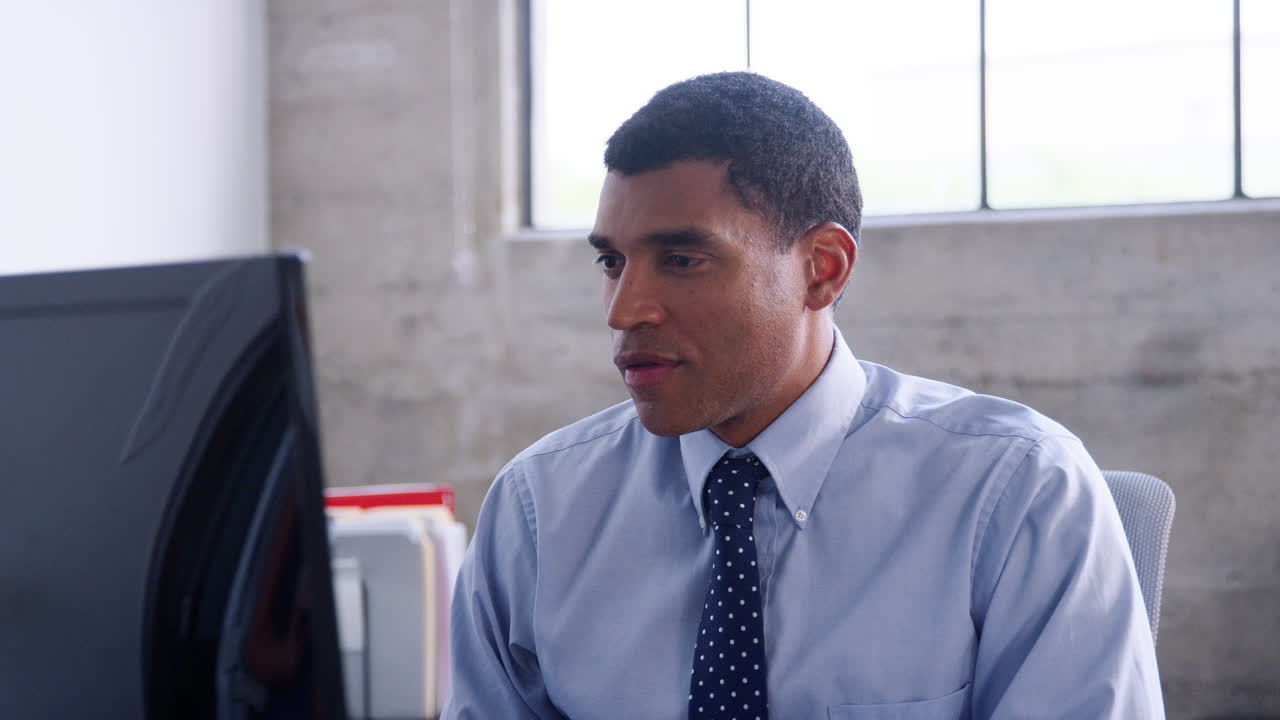 un hombre de negocios de raza mixta trabajando en su oficina se vuelve hacia la cámara.