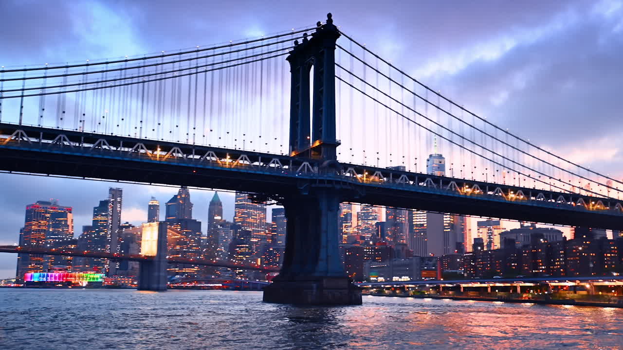 Gorgeous Manhattan Bridge switching on lights at dusk time. Luminous skyline of New York at backdrop