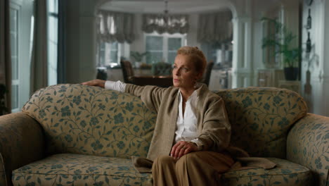 pensive senior woman looking aside in classic interior