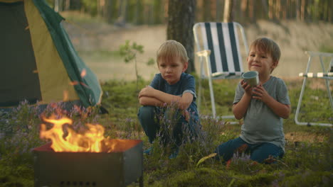 Kinder-Sitzen-Am-Feuer-Und-Schauen-Auf-Das-Feuer-Und-Spielen-Mit-Stöcken