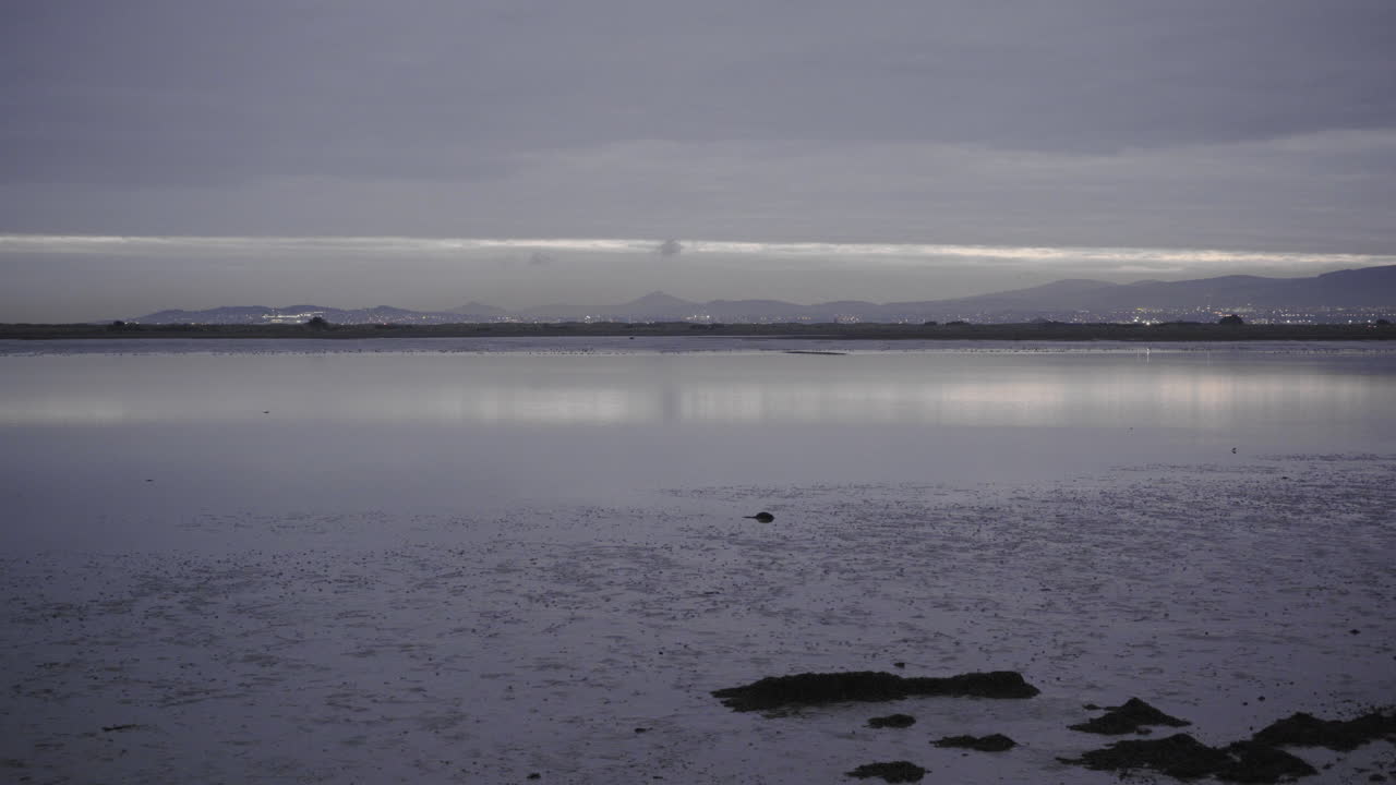 Panning shot of inlet bay near Donaghmede strand in Ireland at sunset, overcast. In 4K