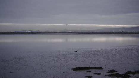 panning shot of inlet bay near donaghmede strand in ireland at sunset, overcast. in 4k