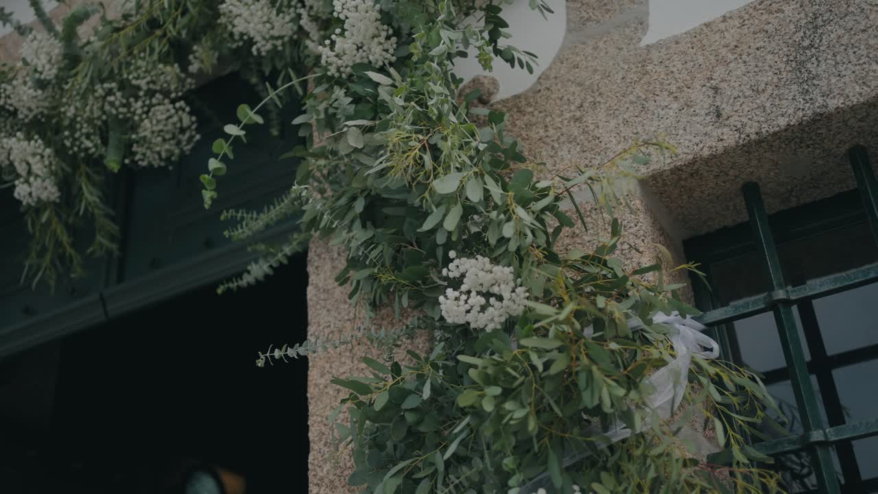 싱그러운 흰색 꽃과 푸른 잎사귀가 소박한 돌 문을 장식하고 있어요