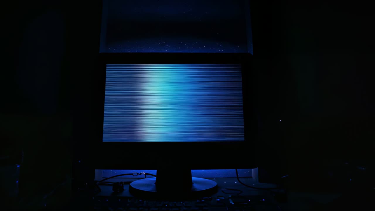 Scan line glitching computer monitor, filling frame with blue glitches on dim desk with cables
