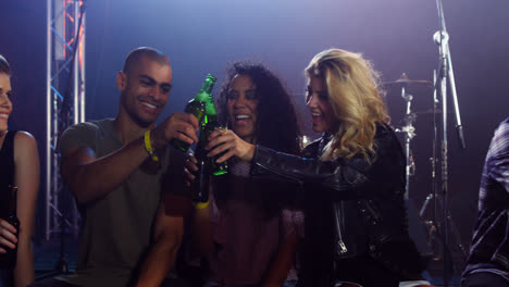 group of friends toasting beer bottles at a concert 4k