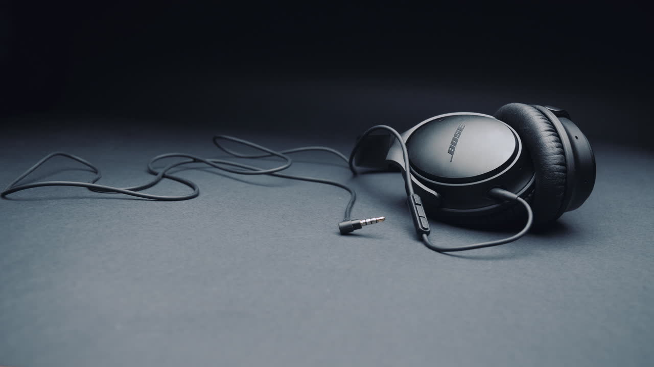 Black headphones BOSE on a pure gray background, together with the cable. Camera movement from left to right.