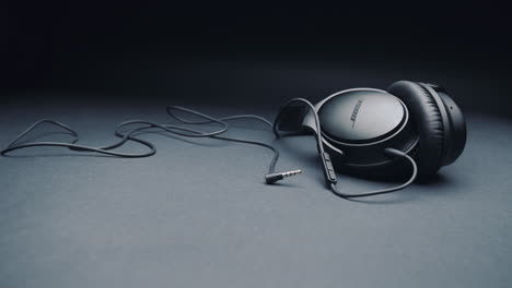 black headphones bose on a pure gray background, together with the cable. camera movement from left to right.